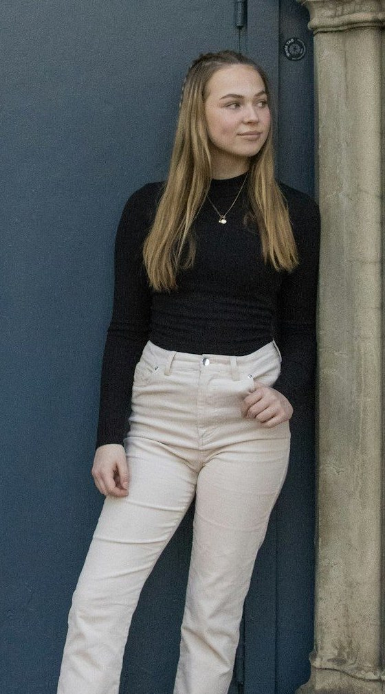 A person wearing a black top, a necklace and cream jeans as Rehang detects each garment and adds it to a digital wardrobe